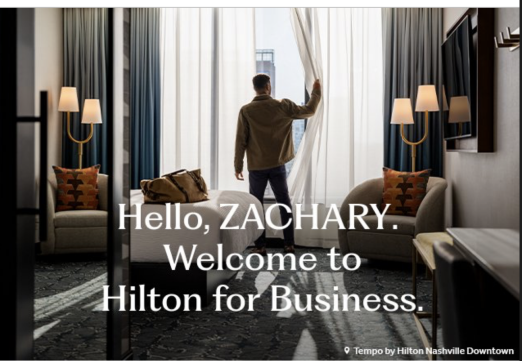 a man standing in a hotel room opening a curtain